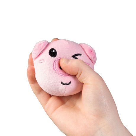Child's hand squeezing pink pig farm animal squishy plush sensory toy demonstrating soft sugar-filled texture