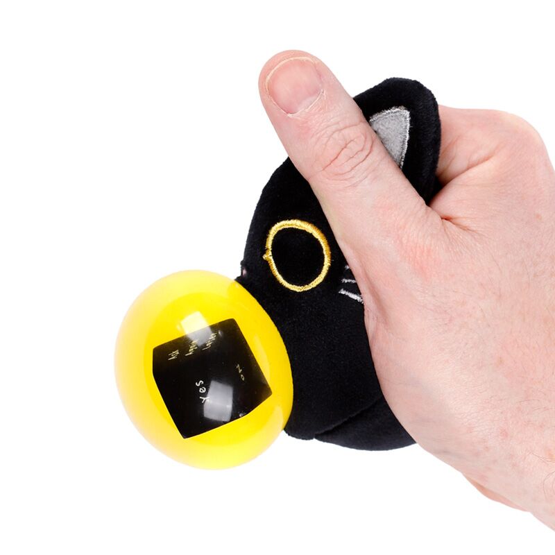 Hand squeezing Fortune Squeezies Lucky the Black Cat magic fortune teller plush squeezy toy with yellow magic ball showing yes answer on fortune dice