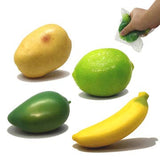 Four fruits (potato, lime, mango, banana) on a white background with a hand holding a small bag.