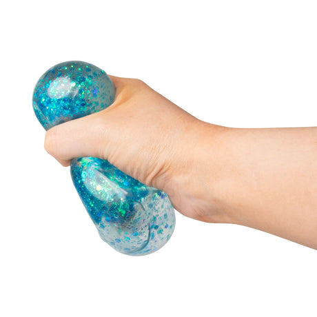 Hand squeezing a blue glitter sugar cube showing the gel deforming between fingers