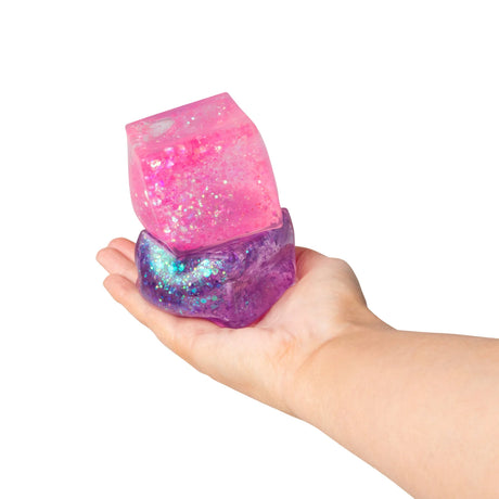 Hand holding pink and purple glitter sugar cubes stacked showing size and glitter detail