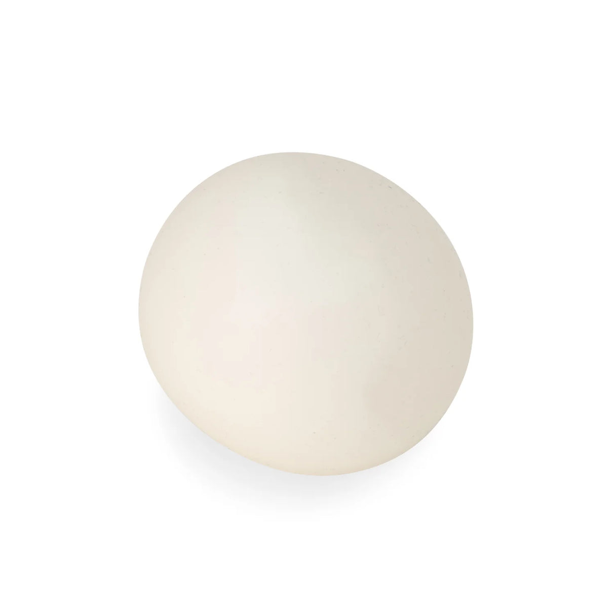 Glow in the dark squish ball in daylight showing its soft off-white appearance on a white background