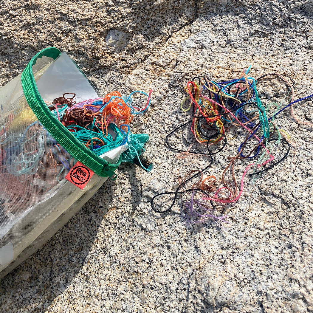 yarn spilling out of a green mesh bag, with a red "Petra Boase" tag visible