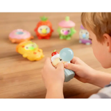 Child squeezing a cupcake Gum Gums figure blowing a blue bubble beside other characters