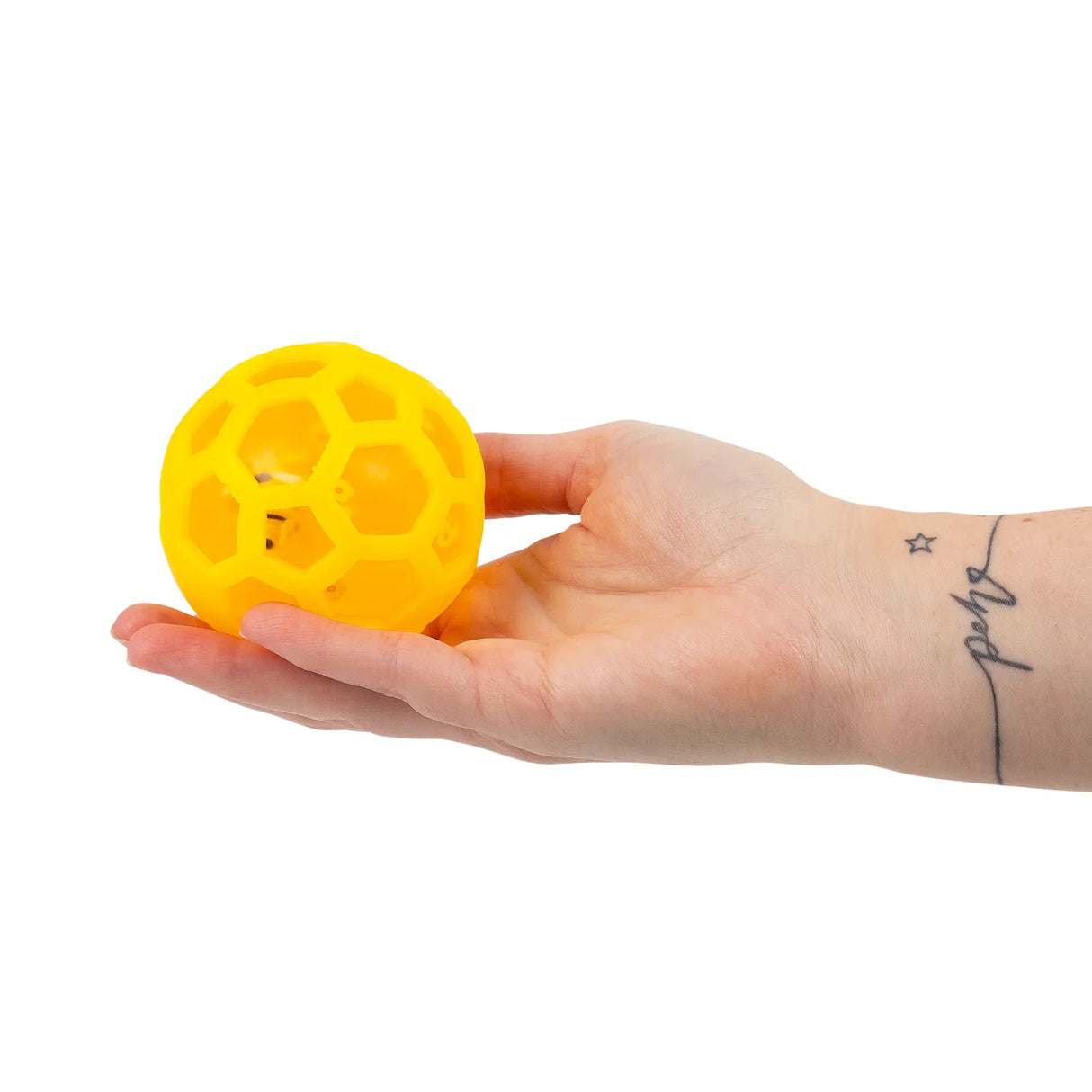 Honey bee fusion squish ball resting in an open palm showing yellow honeycomb texture