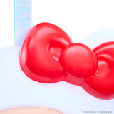 Close-up of a red Hello Kitty bow on a white headband with a light blue ribbon, with a small portion of a peach-colored face visible at the bottom.