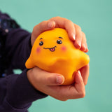Two hands cupping and squeezing the orange Jelly Squish kawaii jellyfish squishy