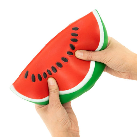 Two hands squeezing a jumbo watermelon slice squishy toy