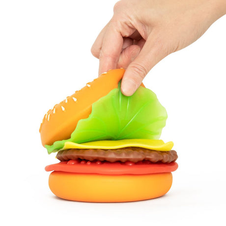 Hand lifting the lettuce layer off a stacked Keycraft Big Squij Peel 'N Stack Burger squishy toy