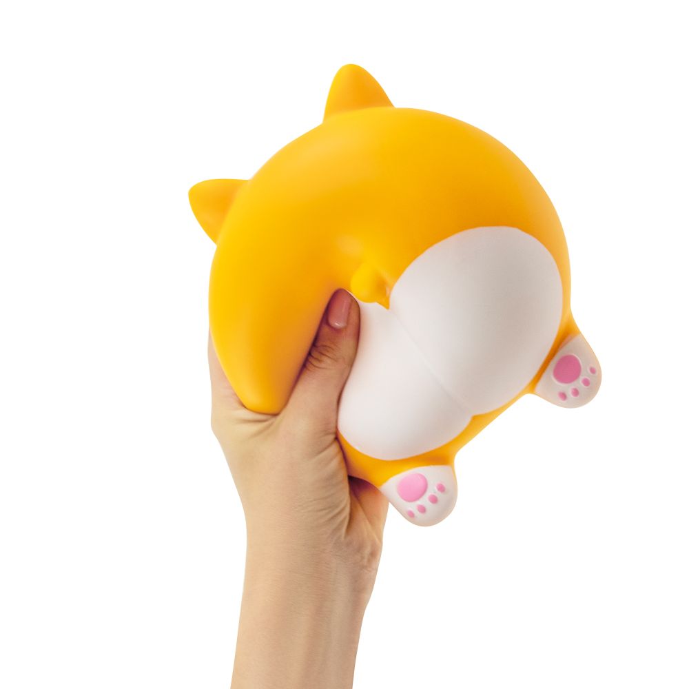Hand squeezing the Keycraft Big Squij Corgi Butt squishy toy to show its soft, slow-rise texture