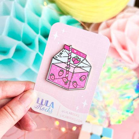 Lula Rocks Strawberry Milk enamel pin on pink backing card, pastel lifestyle shot