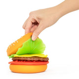 Hand peeling apart the top bun layer of a Peel N Stack Burger sensory toy to reveal layered ingredients