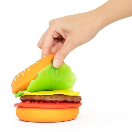 Hand peeling apart the top bun layer of a Peel N Stack Burger sensory toy to reveal layered ingredients