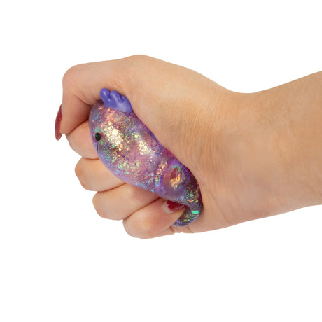 Hand squeezing a purple glitter gel axolotl squishy showing the soft material deforming