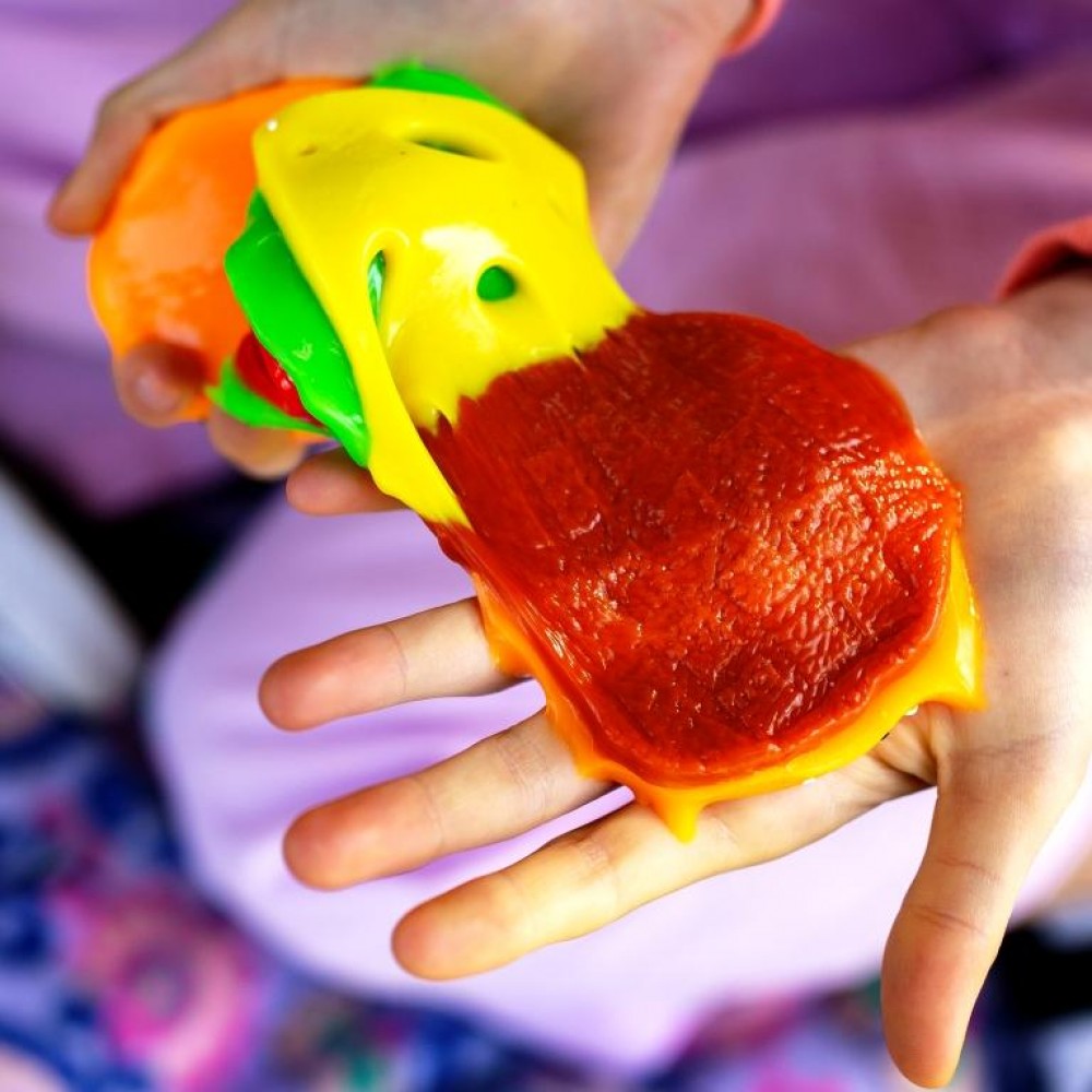 Hands stretching a Mushmeez burger taba squishy showing colourful layered compound spreading across palm