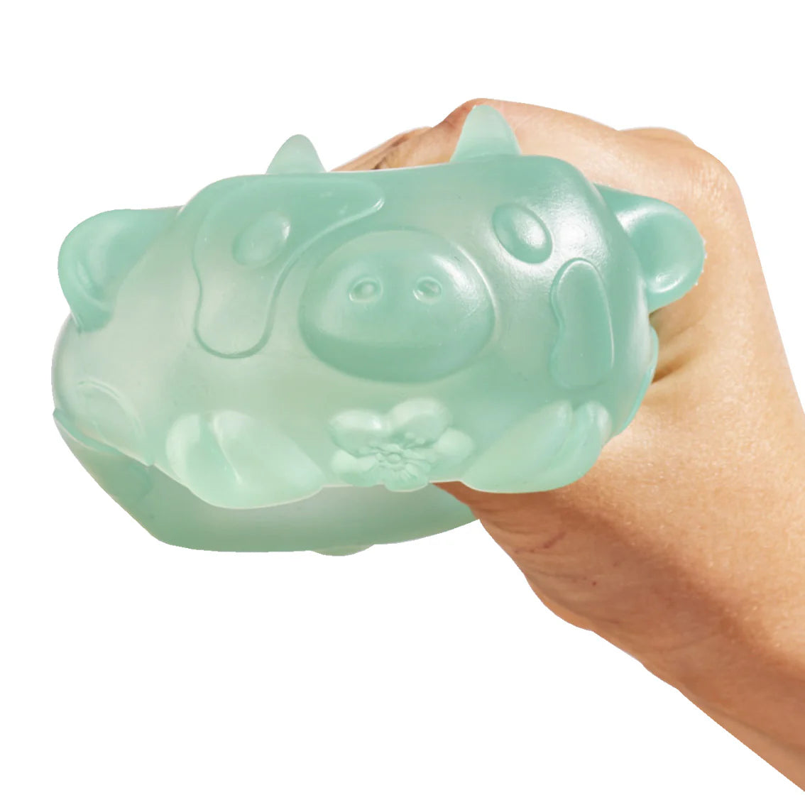 Adult hand squeezing a translucent mint green MushyKinz Jelleez cow squishy, showing its soft firm squish