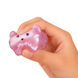 A hand holding a small, glossy, pink pig-shaped squishy toy against a plain white background.