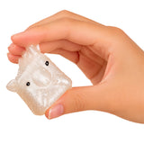 A hand holding a small, translucent, animal-shaped squishy toy with black eyes, shown against a plain white background.