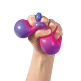 Hand squeezing a pink Nee Doh Colour Change ball revealing a vivid purple colour shift