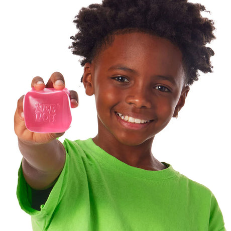 Pink Nee Doh Nice Cube held out showing the embossed Nee Doh logo on the face