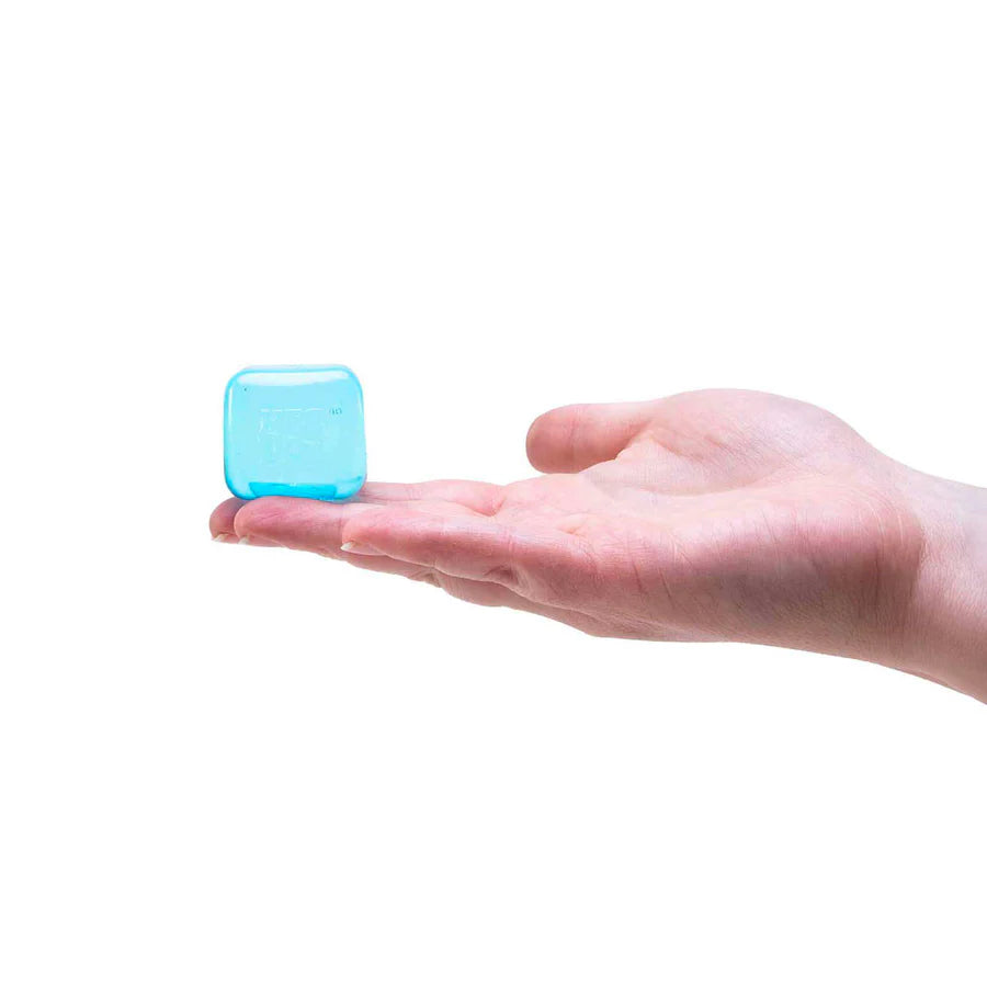 Tiny translucent blue Nee Doh Nice Ice Baby squishy cube balancing on a fingertip in an open palm