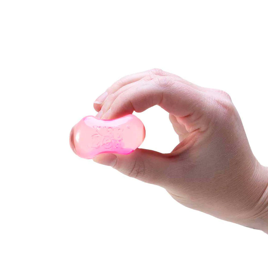 Hand squeezing a translucent pink Nee Doh Nice Ice Baby squishy cube between thumb and fingers