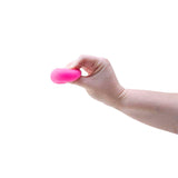 Hand squeezing a pink Nee Doh Teenie Fuzz Ball flat between fingers