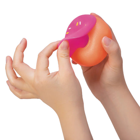 Pink frosting top of a NeeDoh Dohnut being peeled back to show the swappable two-piece design