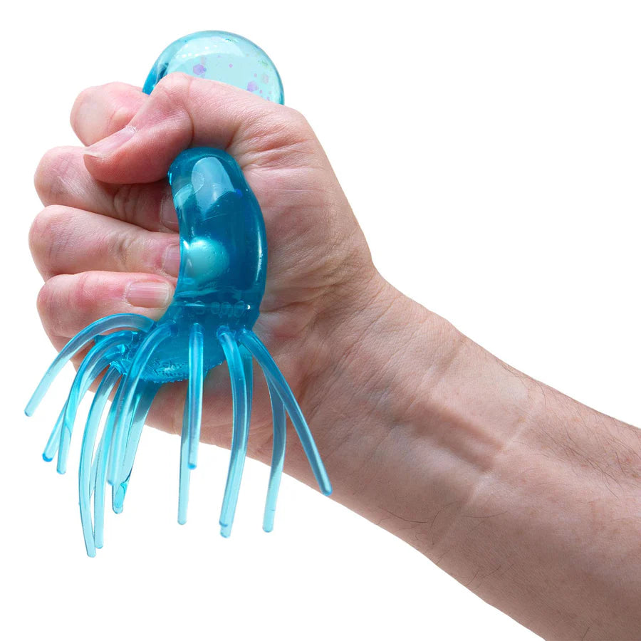 Hand squeezing blue NeeDoh Jelly Squish jellyfish fidget toy in a fist