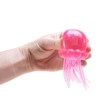 Hand holding a pink jellyfish-shaped toy against a white background