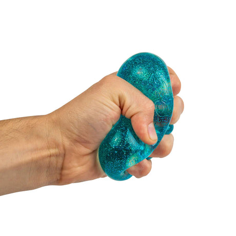 Hand squeezing blue glitter NeeDoh Nice Cube showing the solid squish deformation