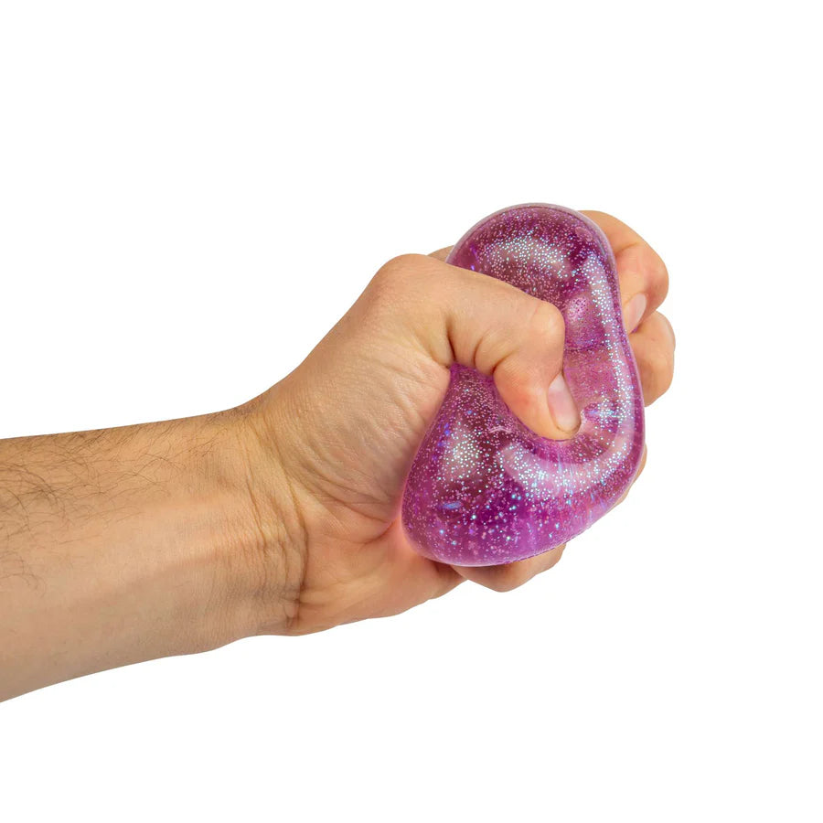 Hand squeezing purple glitter NeeDoh Nice Cube showing the solid squish deformation