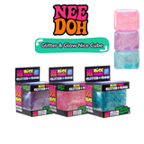 Three NeeDoh Glitter and Glow Nice Cube boxes in purple, pink and blue with stacked cubes alongside