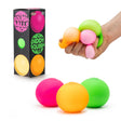 All three neon squish balls alongside their box, with a hand squeezing all three at once to show stretchiness