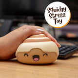 Hand squeezing the Nice Buns squishy stress toy on a desk next to a keyboard