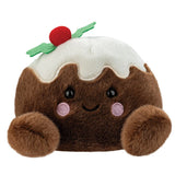 A plush pudding character toy with brown fuzzy body, white frosting, green holly leaves, and a red berry on top, set against a plain white background.