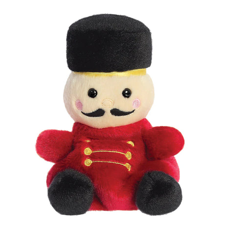 Palm Pals Marius Nutcracker plush, a small palm-sized stuffed nutcracker soldier with a cream face, black embroidered moustache, a tall black hat with gold band, a red uniform with gold embroidered detail, and black feet