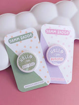 Peachy Lane Studio Hello I Am Autistic badge, sage green and lilac variants flat lay
