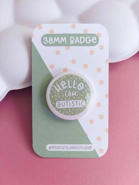 Peachy Lane Studio Hello I Am Autistic 38mm badge, sage green, clean pink background