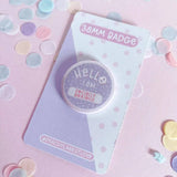 Peachy Lane Studio Hello I Am Socially Anxious badge, lilac, flat lay with pastel confetti