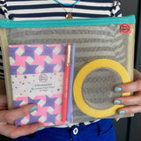 Person holding a transparent pouch with notebooks and yellow tape.
