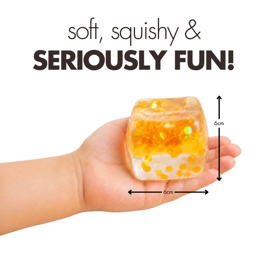 Hand holding an orange glitter Play Hub Squishy Cube showing its 6cm by 6cm size