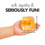 Hand holding an orange glitter Play Hub Squishy Cube showing its 6cm by 6cm size