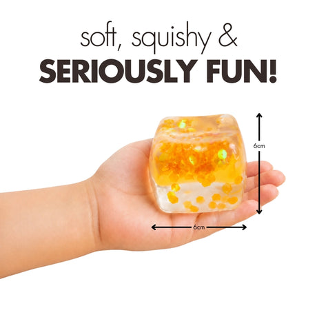 Hand holding an orange glitter Play Hub Squishy Cube showing its 6cm by 6cm size