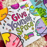 Completed colouring page reading Give Yourself Space surrounded by kawaii planet and space characters