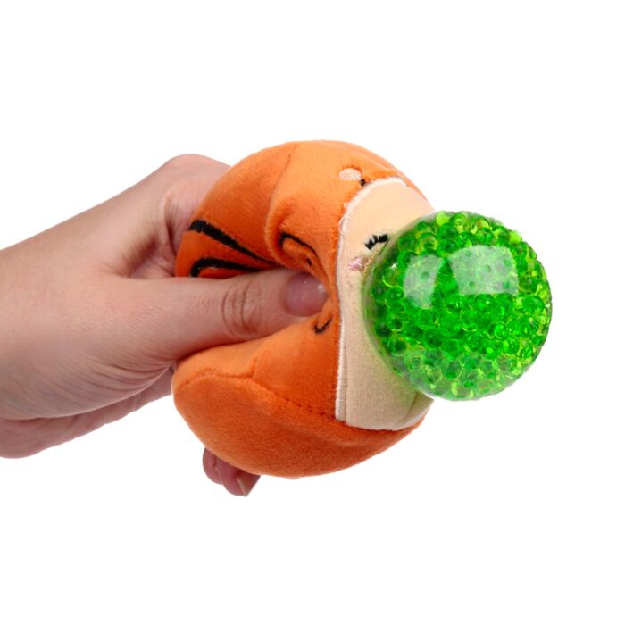 Hand squeezing an orange plush snail Queasy Squeezie causing green water bead nose to bulge out