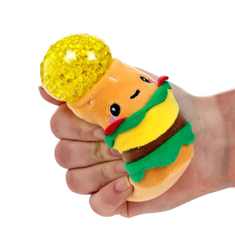 Fist squeezing a plush burger Queasy Squeezie causing a large yellow water bead top to bulge out