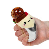 Hand squeezing a silver foil burrito Queasy Squeezie causing brown water bead top to bulge out