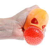 Hand squeezing the red gel bead centre of a Queasy Squeezies pumpkin plush toy