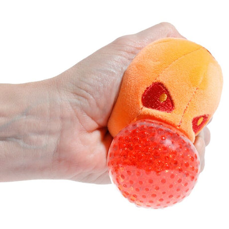 Hand squeezing the red gel bead centre of a Queasy Squeezies pumpkin plush toy